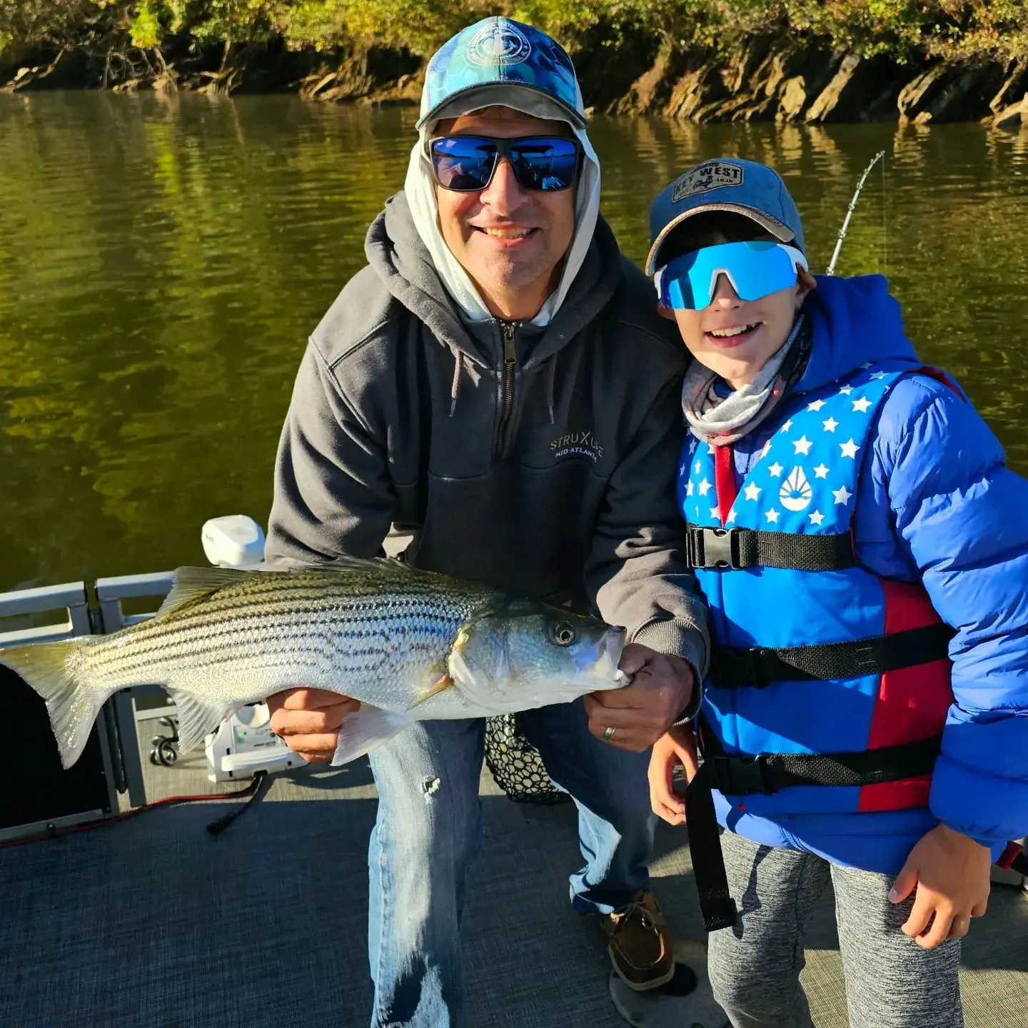 Anglers holding a large striped bass caught on Lake Allatoona