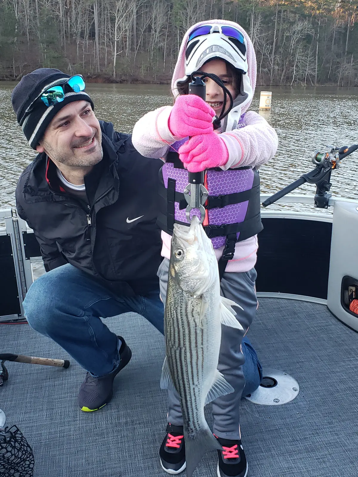 A young girl and her father holding a striped bass on Lake Allatoona
